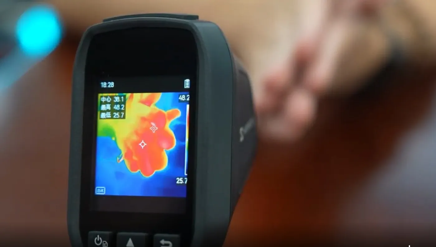 Thermal imaging camera showing a hand glowing red and orange with heat after contact with a graphene pad
